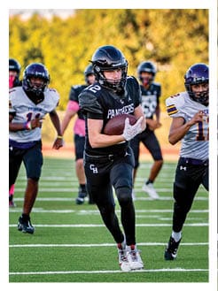 Two football players wearing black jerseys and holding hands. Description generated by AI