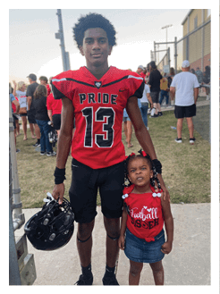 Two football players wearing black jerseys and holding hands. Description generated by AI