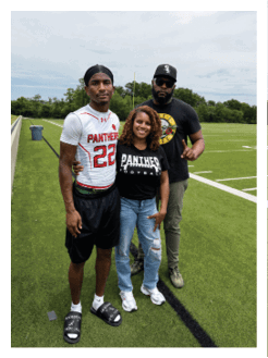 Two football players wearing black jerseys and holding hands. Description generated by AI