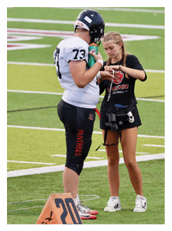 Two football players wearing black jerseys and holding hands. Description generated by AI