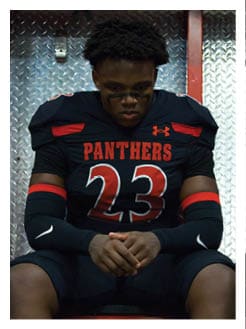 Two football players wearing black jerseys and holding hands. Description generated by AI