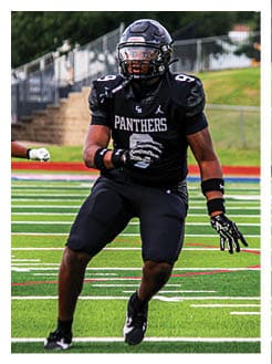 Two football players wearing black jerseys and holding hands. Description generated by AI