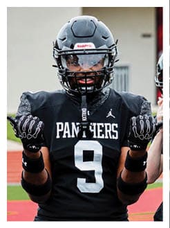 Two football players wearing black jerseys and holding hands. Description generated by AI