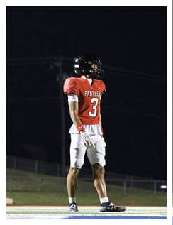 A football player wearing a blue and red jersey. Description generated by AI