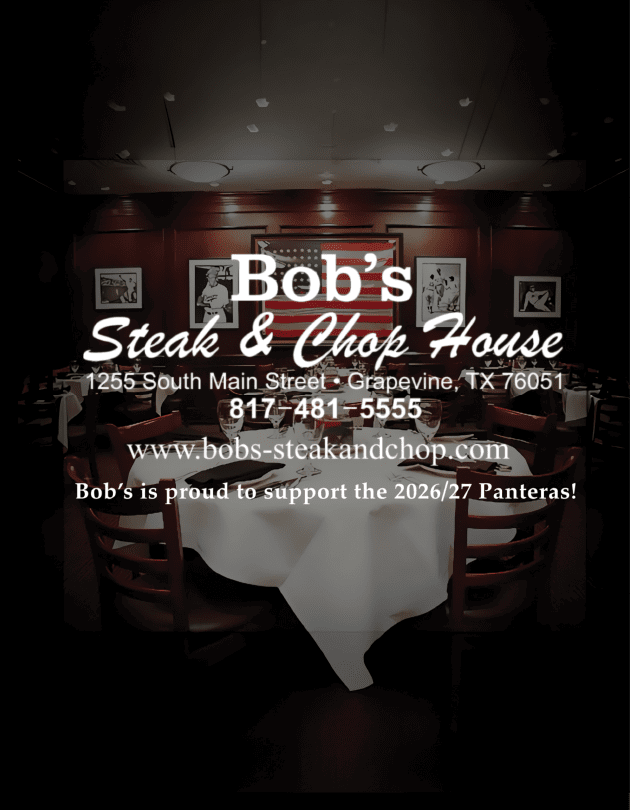 A dimly lit restaurant interior with framed artwork on dark wood-paneled walls and partially visible text advertising a steak and grill establishment. Description generated by AI