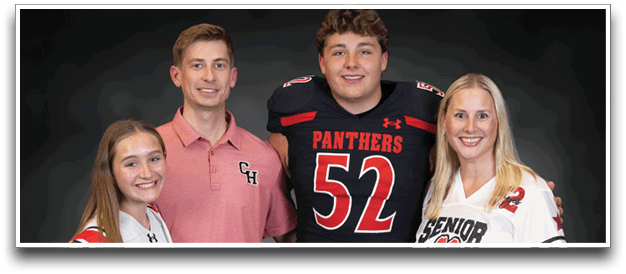 Four people wearing sports jerseys and holding footballs stand together smiling against a dark background. Description generated by AI