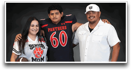 Three people stand together with one person wearing a sports jersey holding a football, another in a football uniform, and the third in a white button-up shirt. Description generated by AI