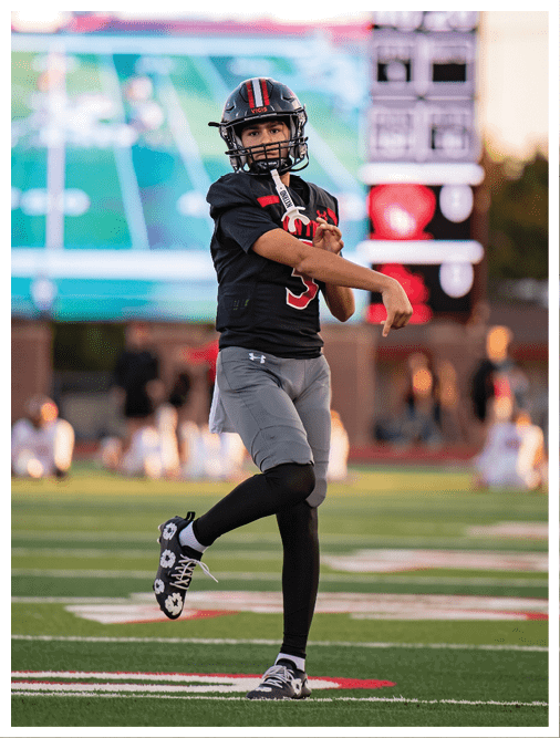 Two football players wearing black jerseys and holding hands. Description generated by AI