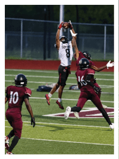 Two football players wearing black jerseys and holding hands. Description generated by AI