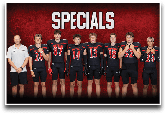 Seven people stand in a row against a red background with the word “SPECIALS" above them, six wearing black football uniforms with red and white accents and one in a white polo shirt and black shorts. Description generated by AI
