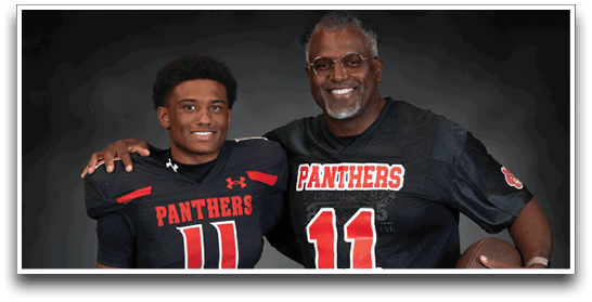 Two people wearing matching black football jerseys with the number 11 and the word Panthers pose together, one holding a football and the other with an arm around the shoulder. Description generated by AI