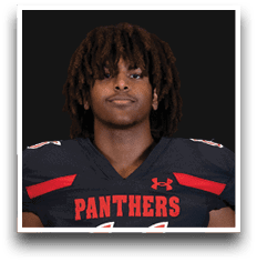 Person with medium-length curly hair wearing a black football jersey with red accents and the word “PANTHERS" on the front. Description generated by AI