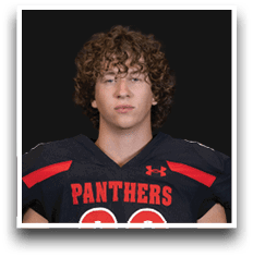 Person with curly hair wearing a black sports jersey with red accents and the word “PANTHERS" across the chest. Description generated by AI