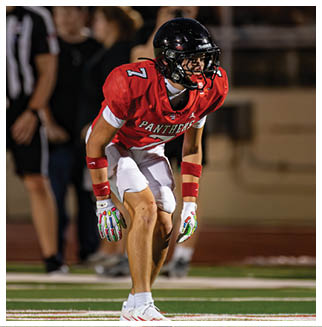 A football player wearing a blue and red jersey. Description generated by AI