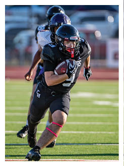 Two football players wearing black jerseys and holding hands. Description generated by AI