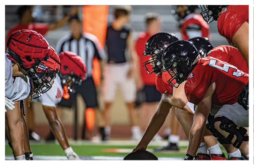 Two football players wearing black jerseys and holding hands. Description generated by AI