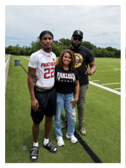 Two football players wearing black jerseys and holding hands. Description generated by AI