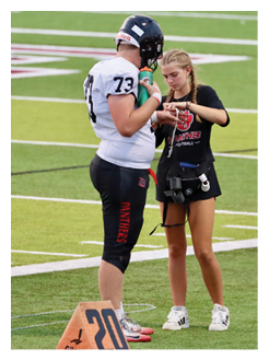 Two football players wearing black jerseys and holding hands. Description generated by AI