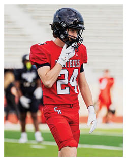 A football player wearing a blue and red jersey. Description generated by AI