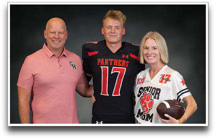Three adults stand together smiling with one wearing a black sports jersey with the number 17 and the word Panthers, another in a pink polo shirt, and the third in a white sports jersey holding a football with the words Senior Mom. Description generated by AI
