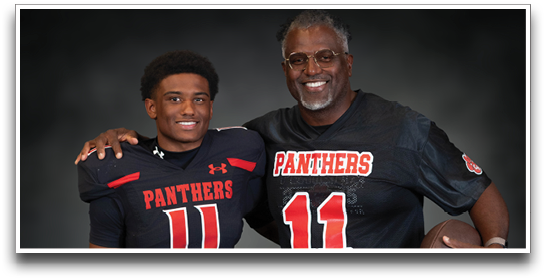 Two people wearing matching black football jerseys with the number 11 and the word Panthers pose together, one holding a football and the other with an arm around the shoulder. Description generated by AI