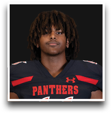 Person with medium-length curly hair wearing a black football jersey with red accents and the word “PANTHERS" on the front. Description generated by AI