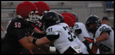 People in football uniforms are engaged in a close physical play on the field during a game. Description generated by AI