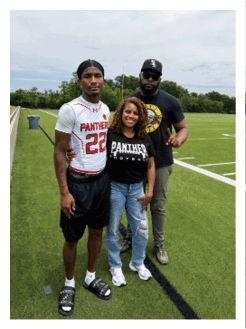 Two football players wearing black jerseys and holding hands. Description generated by AI