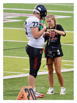 Two football players wearing black jerseys and holding hands. Description generated by AI