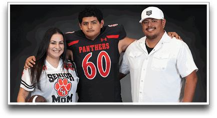 Three people stand together with one person wearing a sports jersey holding a football, another in a football uniform, and the third in a white button-up shirt. Description generated by AI