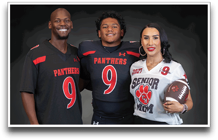 Three adults wearing sports jerseys with the number nine, one holding a football and wearing a “Senior Mom" jersey. Description generated by AI