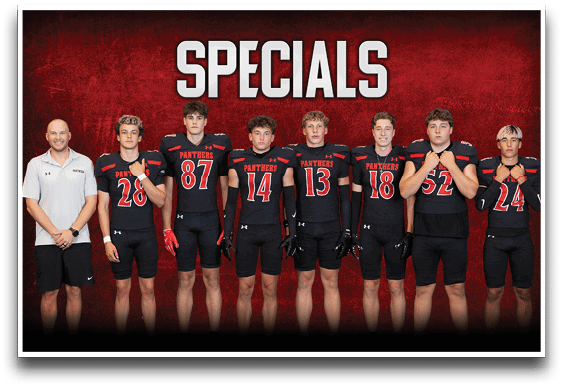 Seven people stand in a row against a red background with the word “SPECIALS" above them, six wearing black football uniforms with red and white accents and one in a white polo shirt and black shorts. Description generated by AI