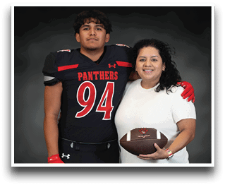 A person wearing a black football uniform with the number 94 and the word Panthers stands with an arm around another person in a white shirt holding a football, both smiling against a dark background. Description generated by AI
