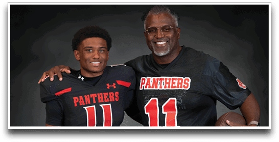 Two people wearing matching black football jerseys with the number 11 and the word Panthers pose together, one holding a football and the other with an arm around the shoulder. Description generated by AI