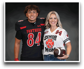 Two people smiling and standing side by side, one wearing a black football uniform with the number 84 and the other wearing a white “Senior Mom" jersey holding a football. Description generated by AI