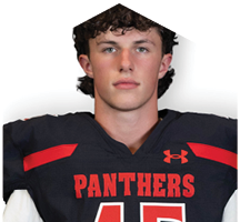 A person with curly hair wearing a black sports jersey with red accents and the word “PANTHERS" on the front. Description generated by AI
