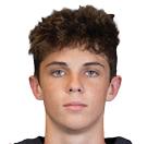 A person with short curly hair wearing a black football jersey with red and white accents and the number 15 stands facing forward. Description generated by AI