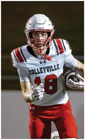 A person wearing a white football helmet and a white and red football uniform with the word “COLLEYVILLE" and the number 18 is running while holding a football. Description generated by AI