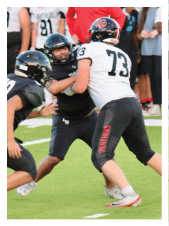 Two football players wearing black jerseys and holding hands. Description generated by AI