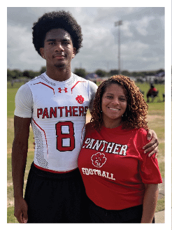 Two football players wearing black jerseys and holding hands. Description generated by AI