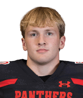 A person with short blond hair wearing a black football jersey with red accents and the word “PANTHERS" on the front is looking straight ahead. Description generated by AI