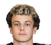 A person with curly hair wearing a black football jersey with red and white accents and the number 28 standing against a white background. Description generated by AI