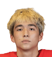 Person with short, tousled blond hair wearing a red sports jersey looking directly at the camera. Description generated by AI