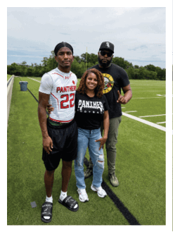 Two football players wearing black jerseys and holding hands. Description generated by AI