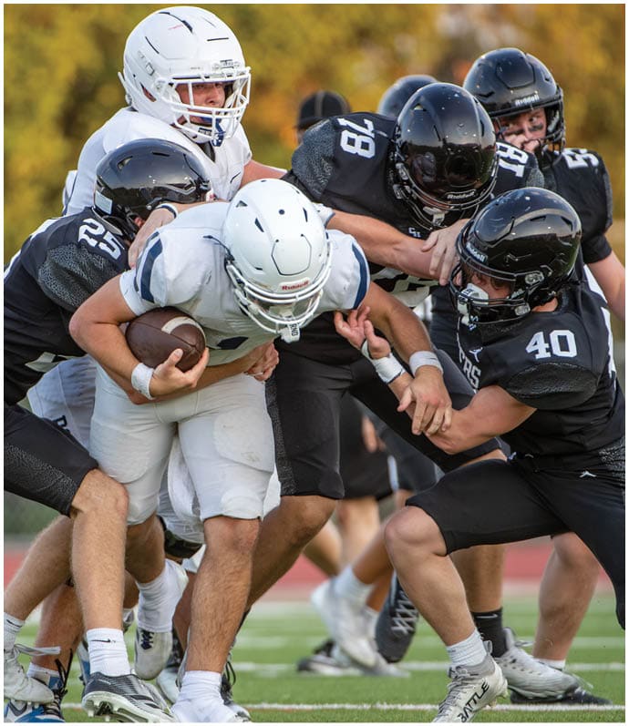 Two people in football uniforms and helmets are engaged in a physical struggle during a game. Description generated by AI