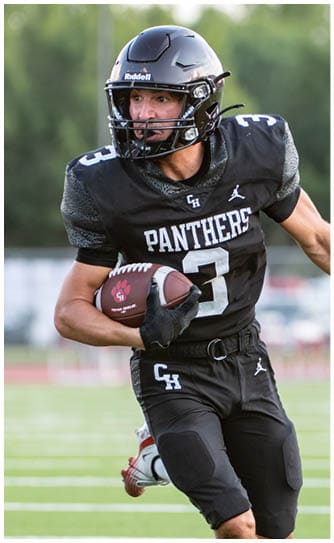 A person wearing a black football uniform with the word Panthers and the number 3 is running on a field while holding a football. Description generated by AI