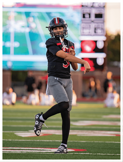 Two football players wearing black jerseys and holding hands. Description generated by AI