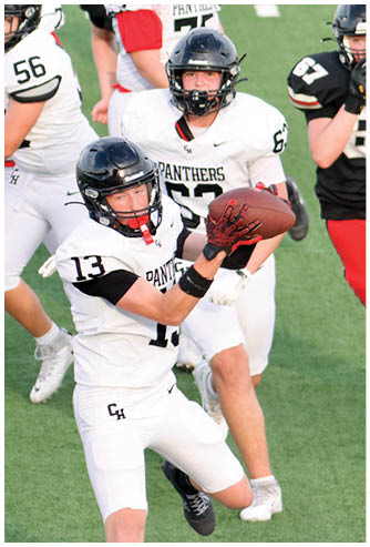 Two people wearing football helmets and white jerseys with “Panthers" written on them are engaged in a play, with one holding a football. Description generated by AI