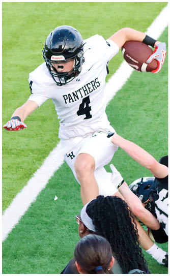 A person wearing a black helmet and white football uniform with the word Panthers and the number 4 is in action on a grassy field. Description generated by AI