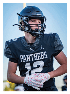 Two football players wearing black jerseys and holding hands. Description generated by AI